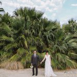 Bride and groom holding hands on sandy landscape