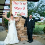 Bride and groom celebrating under sign that says "This is it! Mike and Phyllis".