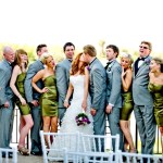 Bride and groom smooching as wedding party smiles