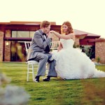 Groom kissing bride's hand while sitting on golf course