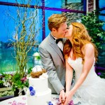 Bride and groom kissing while cutting cake