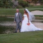Bride and groom with orange flowers walking on golf course 
