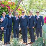 Groomsmen posing amongst the trees and flowers 