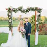 Bride and groom posing under wedding canopy 