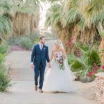 Bride and groom holding hands while walking down path