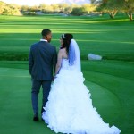 Bride and groom walking on golf course green