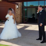 Bride smiling as groom wipes away a tear during first look 