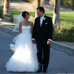 Bride and groom walking down golf course driveway