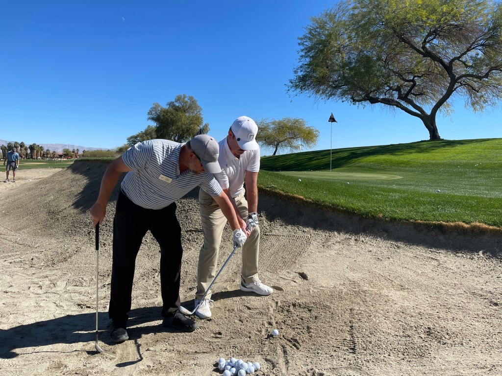 Instructor assisting student in sand trap