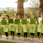 Bridal party in olive robes holding signs that say "Wait till you see her!" 