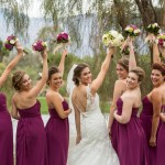 Bride and bridesmaids posing with flowers held up on golf course 