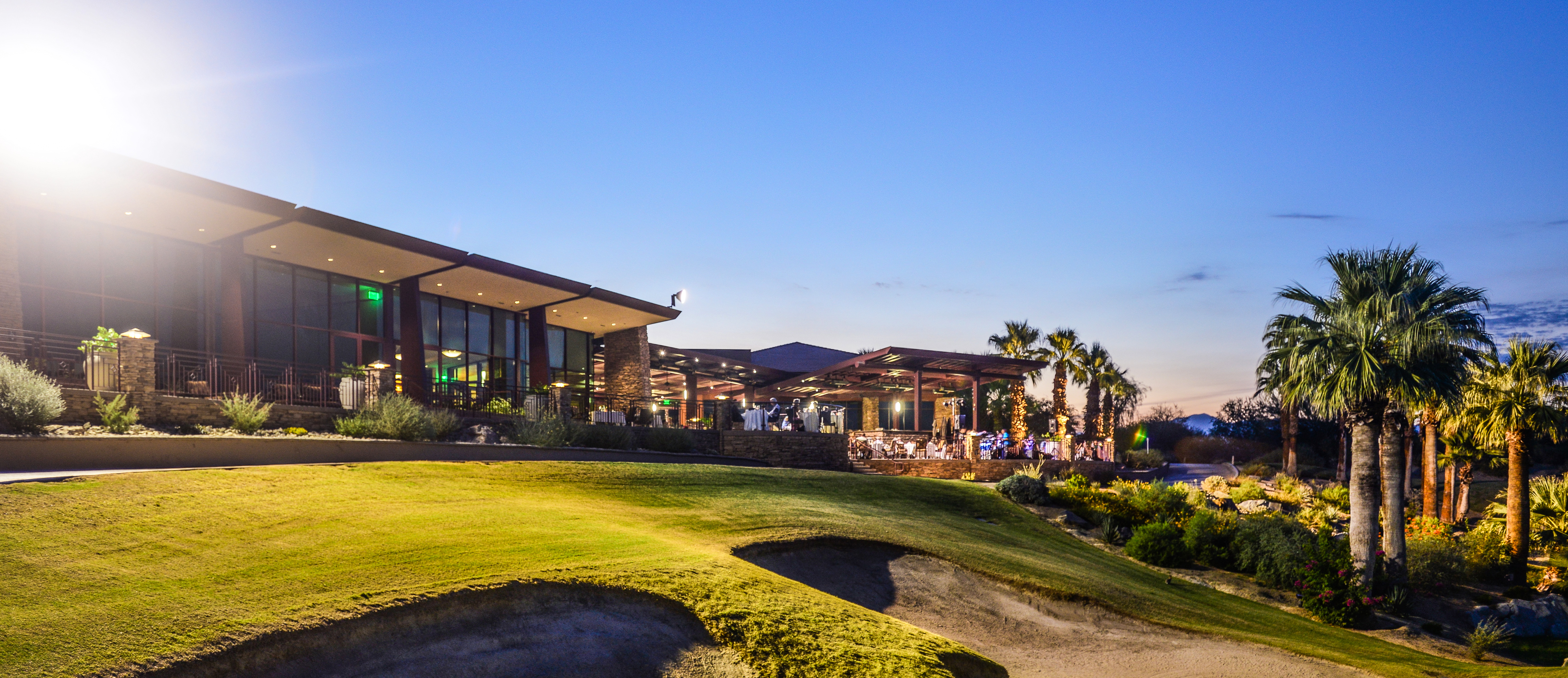 Evening alfresco dining setup on the Lakeview Terrace at Desert Willow Golf Resort, with glowing lights, palm trees, and guests enjoying Music & Dining Under the Stars.