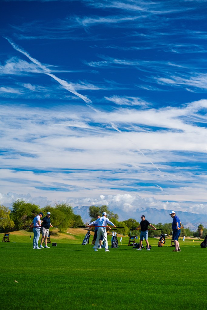 Golfers practicing Stick Mobility stretches on a sunny training tee to improve flexibility and rotational strength