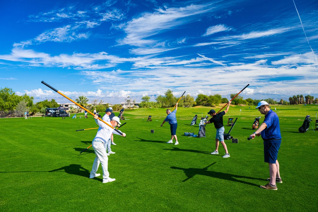 Golfers engaged in a core-focused balance drill during Swing & Stretch class, framed by the natural desert landscape