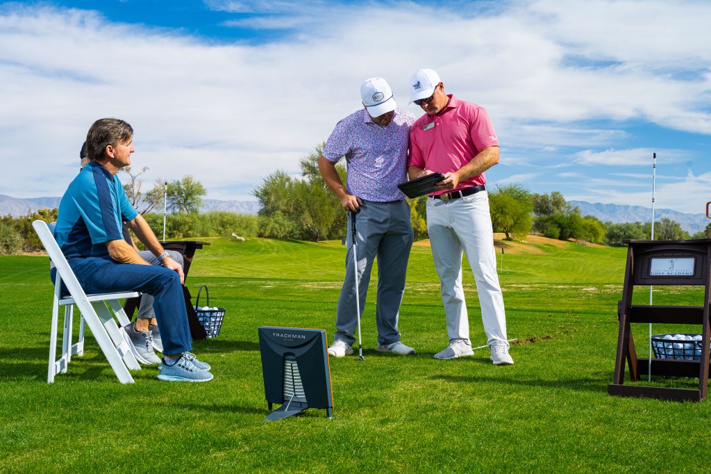 PGA instructors reviewing swing data with a student during the 2-Day Signature Golf School at Desert Willow Golf Resort, featuring TrackMan technology and personalized coaching.