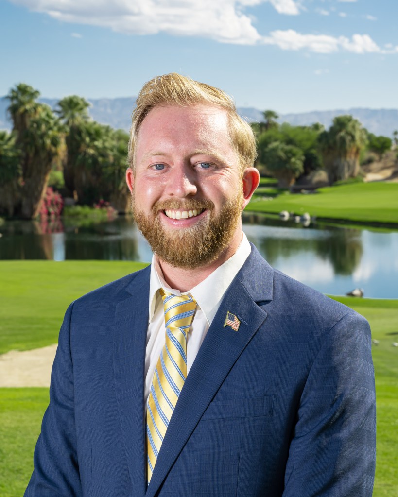 Ryan Szydlowski, PGA Professional, Assistant General Manager and Director of Golf at Palm Desert Golf Academy, headshot portrait in suit and tie with golf course background.