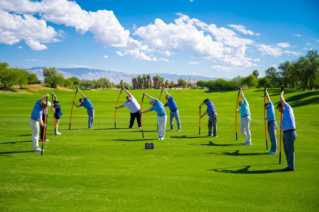 Golf fitness instructor leading a mobility warm-up session at Palm Desert Golf Academy with desert mountains in the background