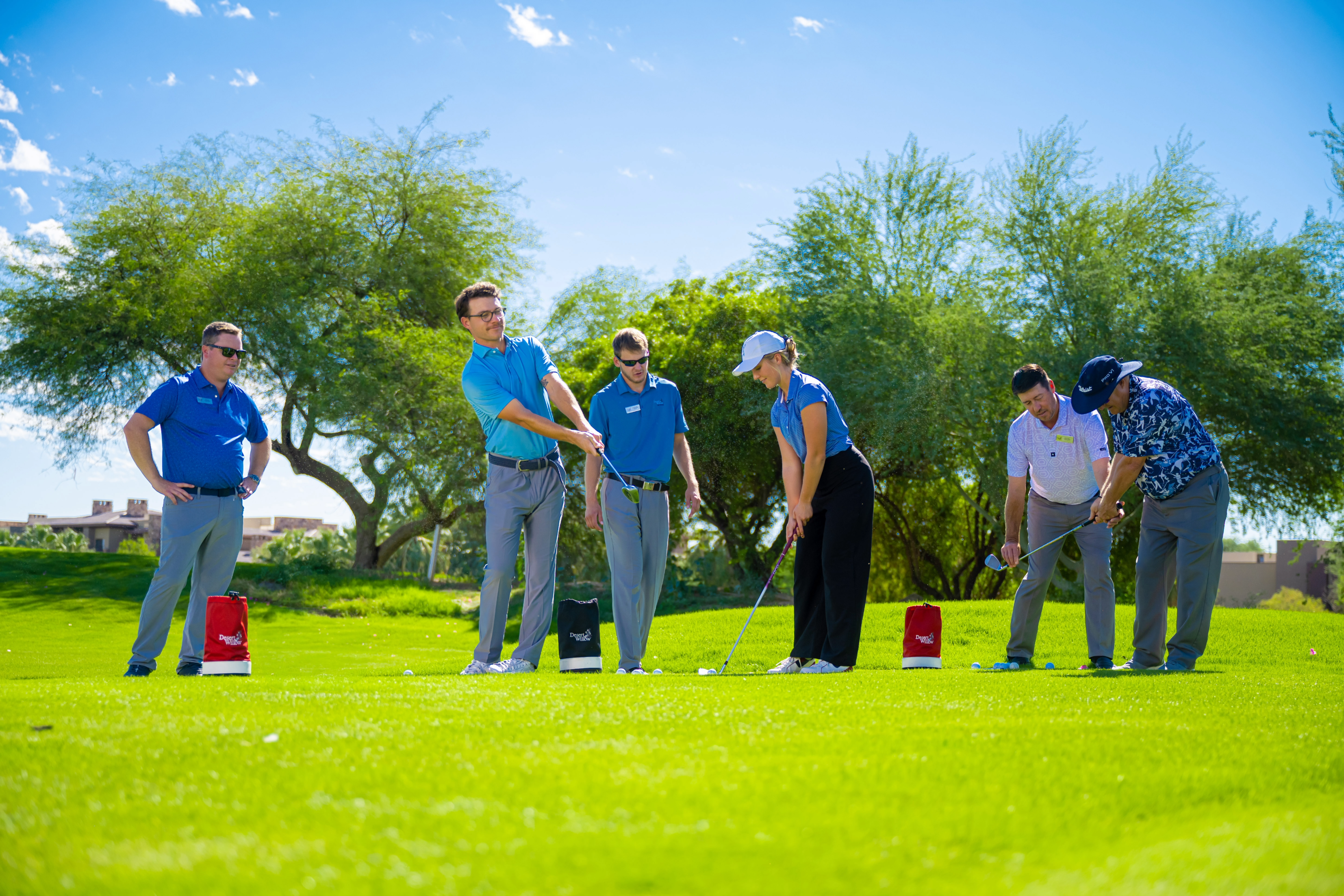 Golfer practicing a short game shot on the lush practice greens at Palm Desert Golf Academy, framed by mountain views and desert landscape at Desert Willow Golf Resort.