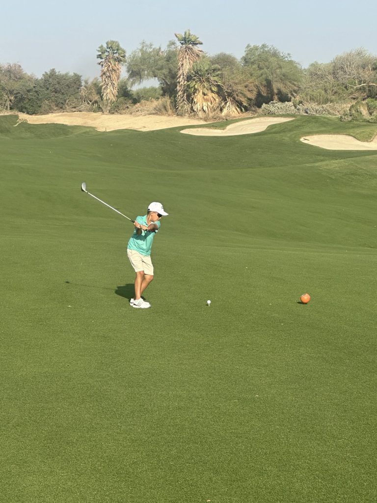 Junior golfer executing an iron shot on the fairway during junior golf instruction at Desert Willow Golf Resort